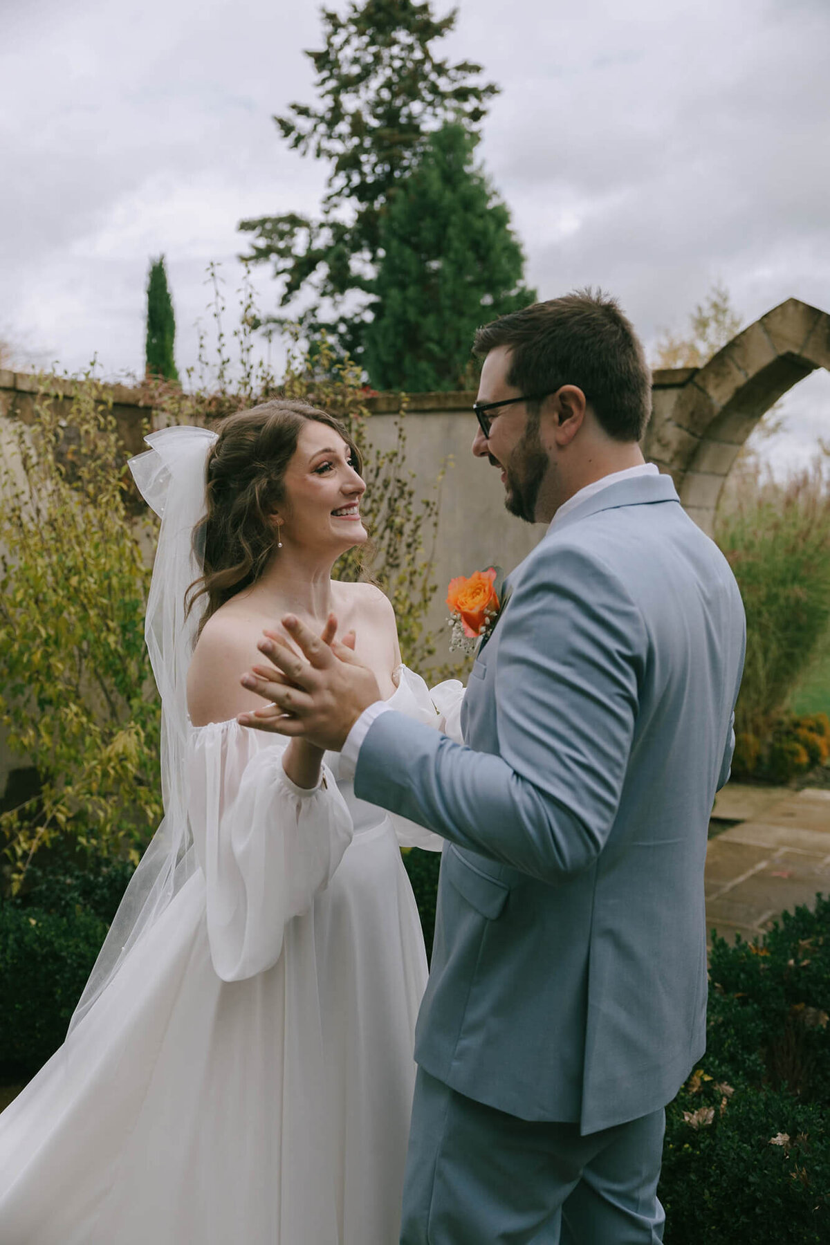 A bride and groom hold hands excitedly during their first look at their wedding planned by Birdie June Events & Rentals. 