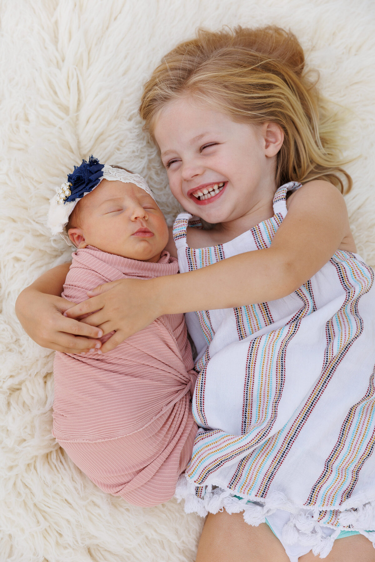 Sister smiling holding a newborn