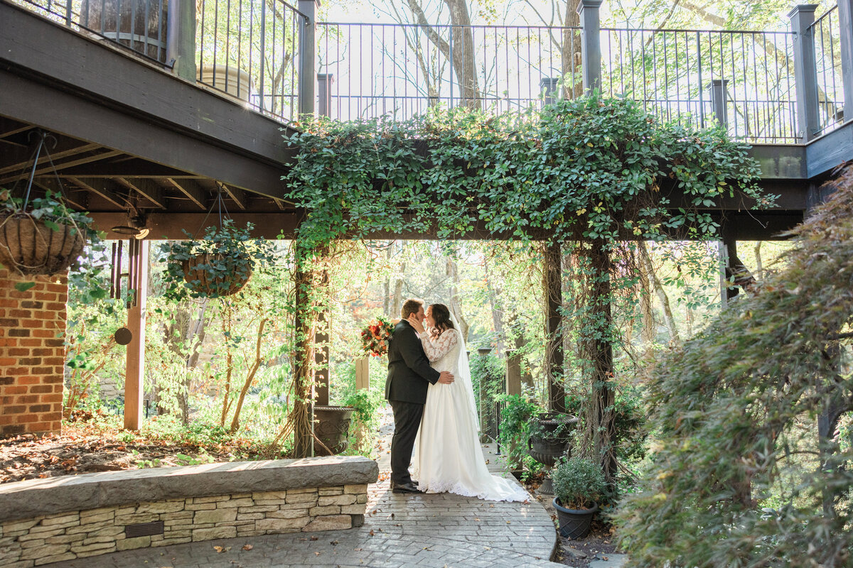 A newlywed couple about to kiss under a small walkway