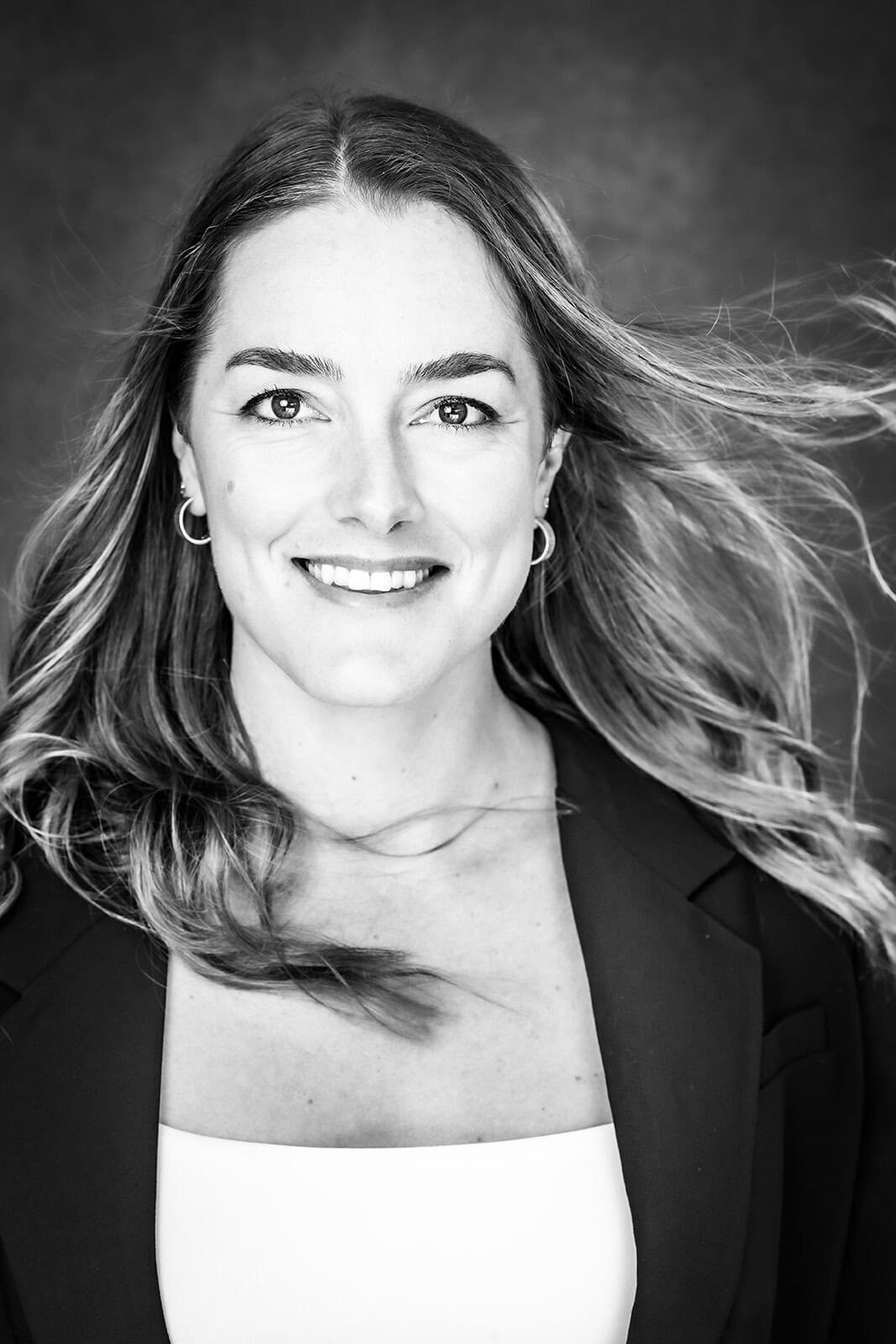 Black and white portrait of a smiling woman with her hair blowing in the wind