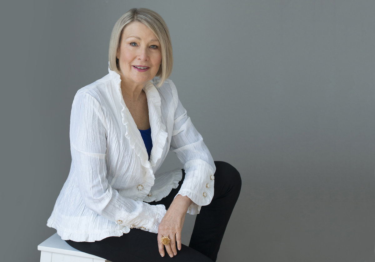 mature woman sitting on stool headshot excellent  and  powerful with grace and  charm wearing white  shirt