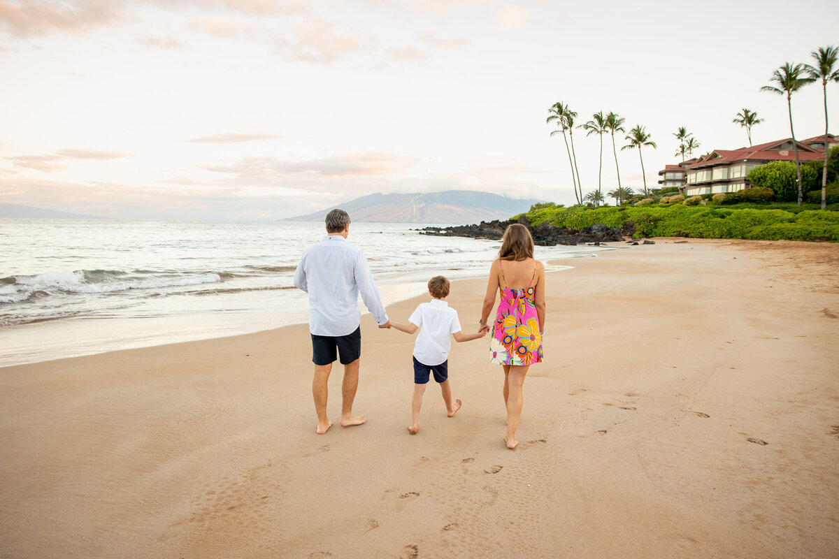 Maui Family Photographers capture mother and father holding hands with son while walking away together