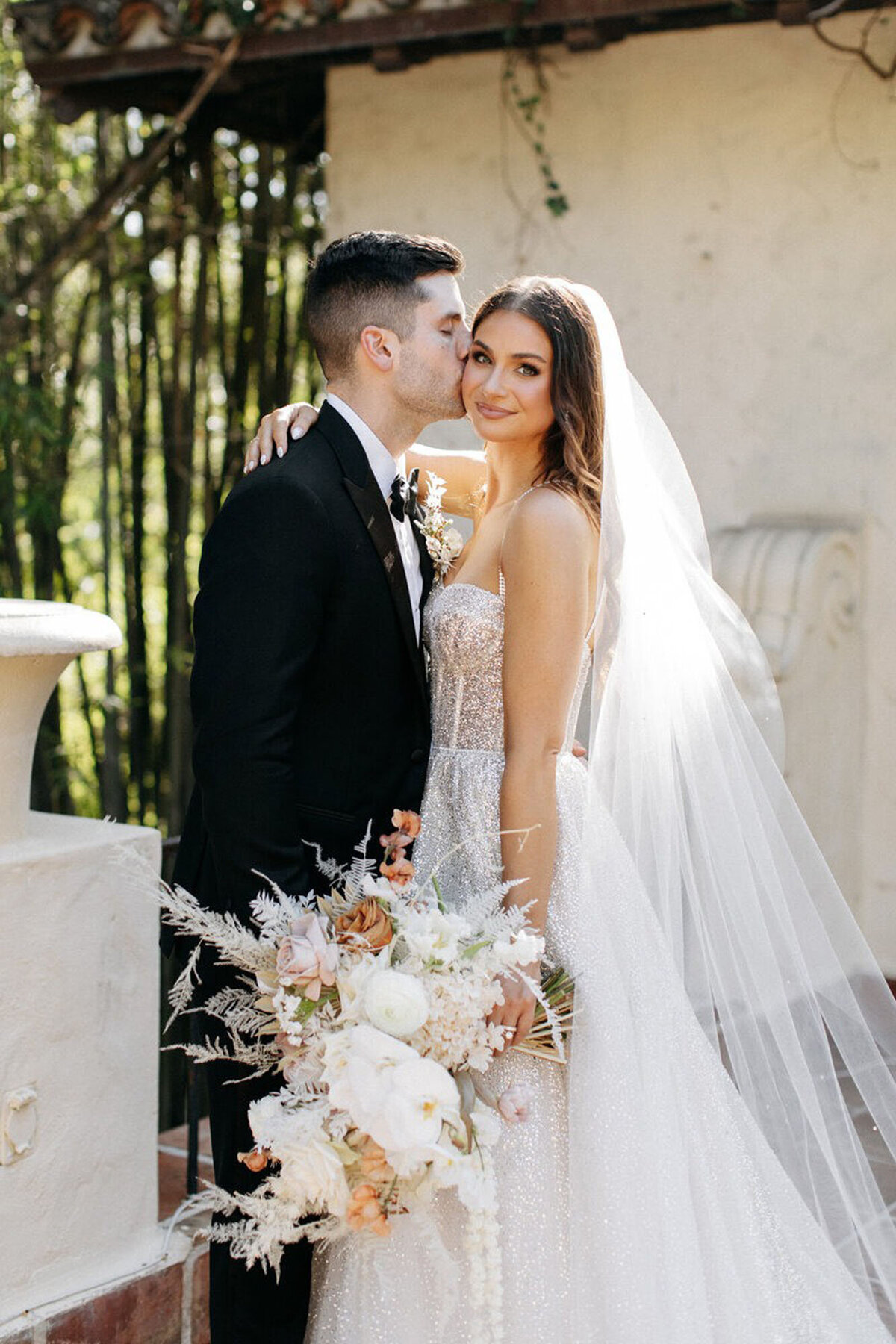 Bride and groom kissing and holding bouquet, taken by orlando wedding photography expert
