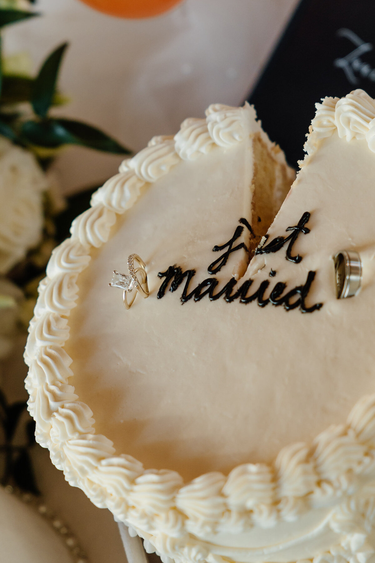 A circular cake with wedding rings in it and a small piece taken out