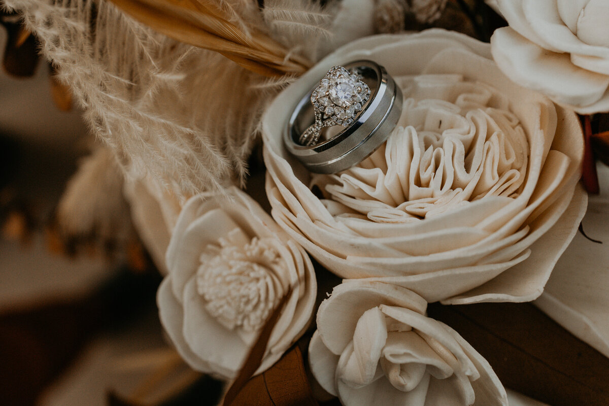 bride and groom wedding rings resting on their bouquet