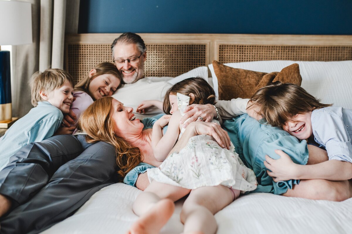 family of 6 cuddling on their bed at home
