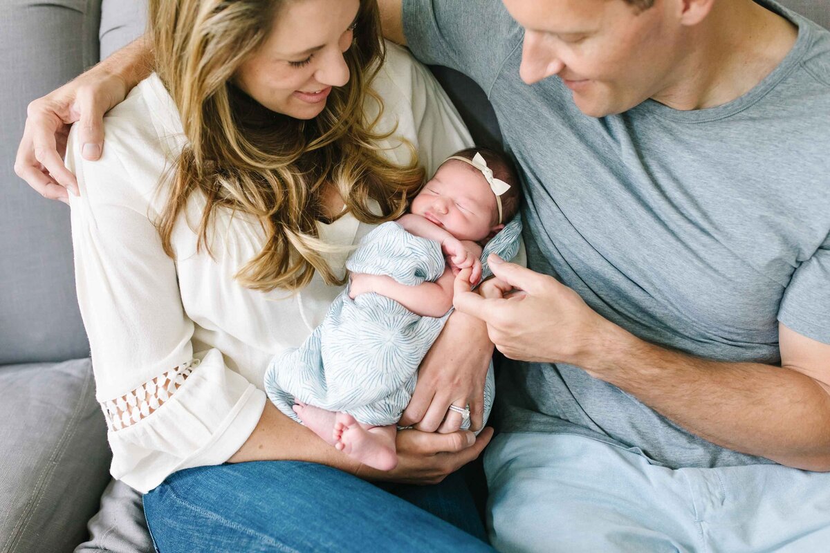 father and mother holding baby and smiling