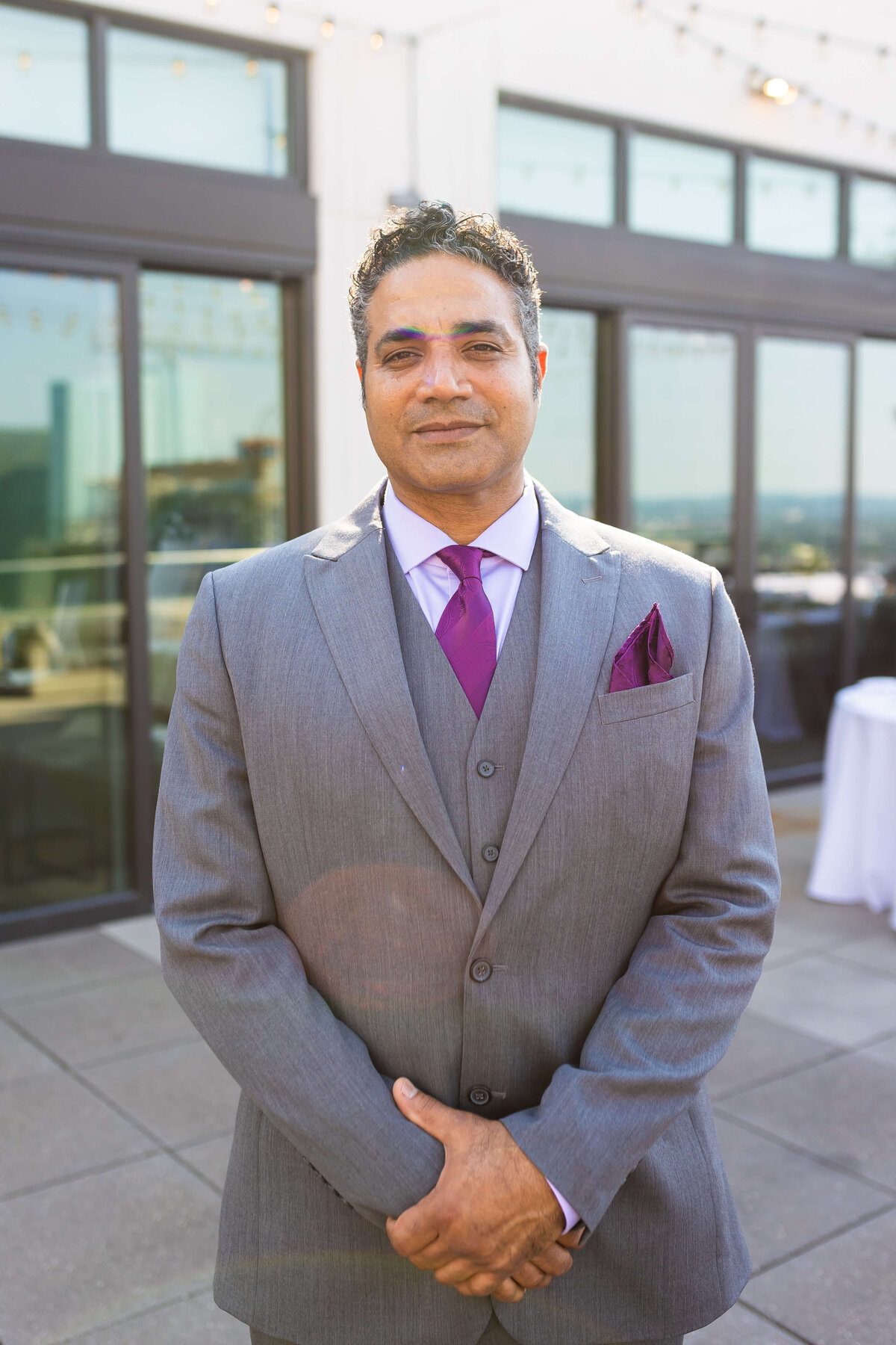 Groom wearing grey suit and purple tie from Mens Warehouse