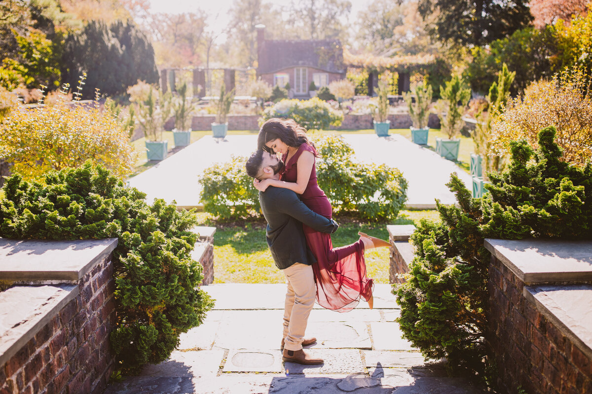 Groom picking up bride at their engagement session at planting fields arboretum in oyster bay