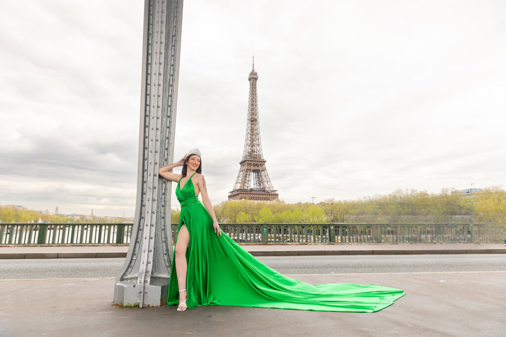 Romantic Paris portrait at Bir Hakeim bridge with woman in green gown leaning on pillar Eiffel Tower view