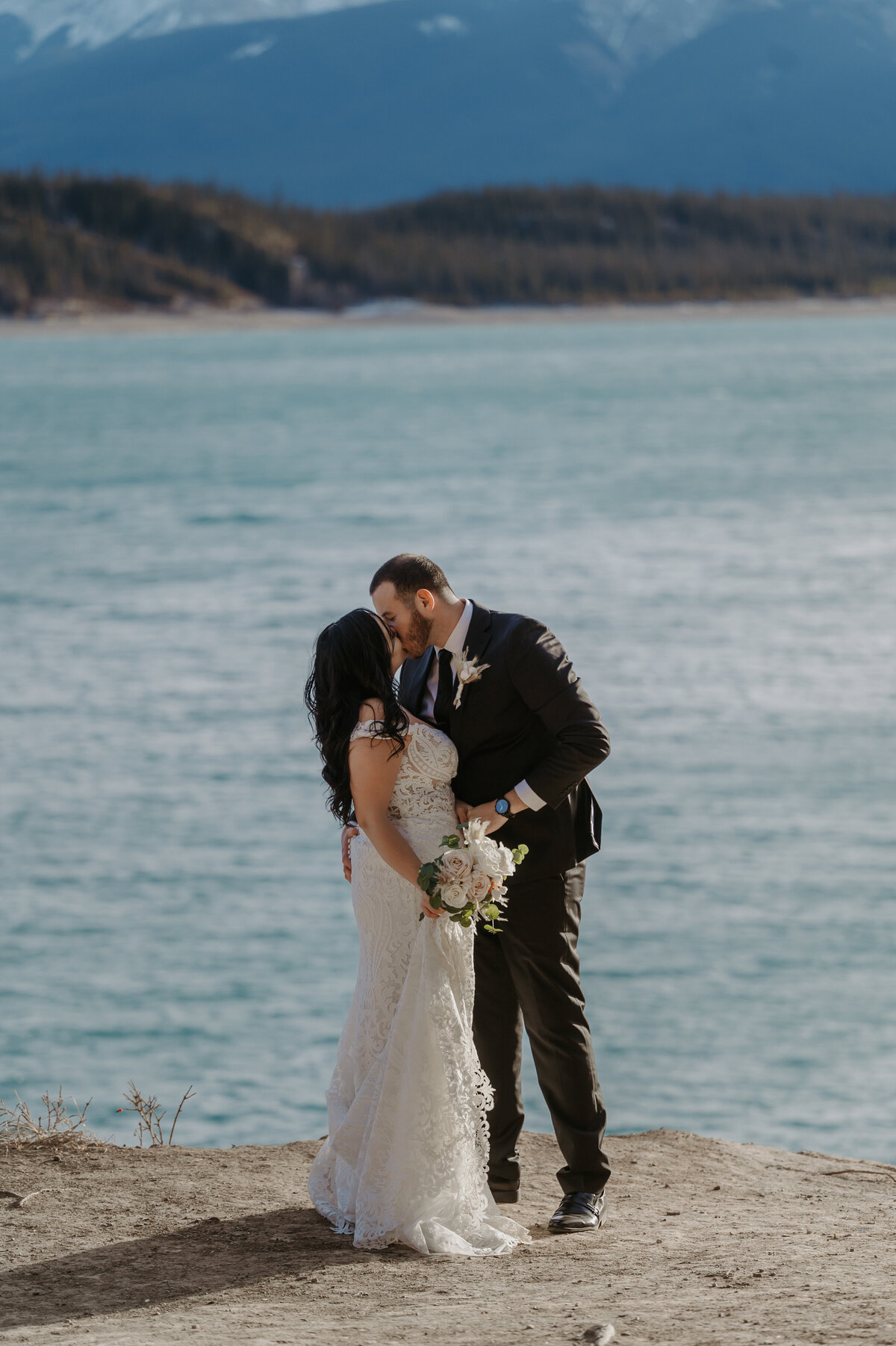 Elopement wedding photograph of the couple kissing in front of lake