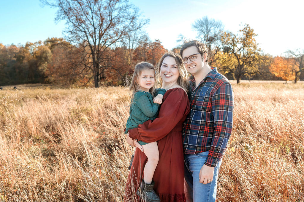 Connecticut family photographer documents joyful family portrait in golden prairie field with beautiful fall foliage backdrop