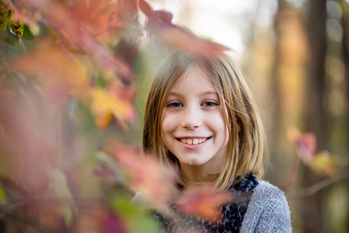 A girl smiling through a tree.
