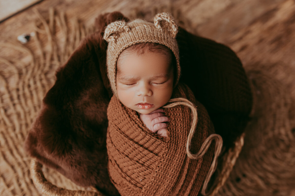 newborn boy wearing bear ears with brown color scheme