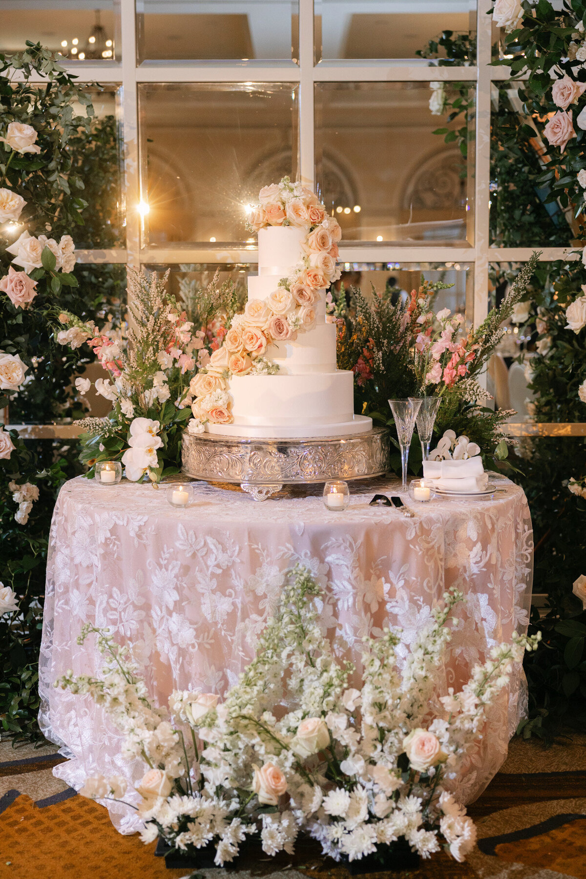 wedding cake table at The Adolphus in Dallas surrounded by abundant and stunning floral arrangements, showcasing an elegant and luxurious reception setup.