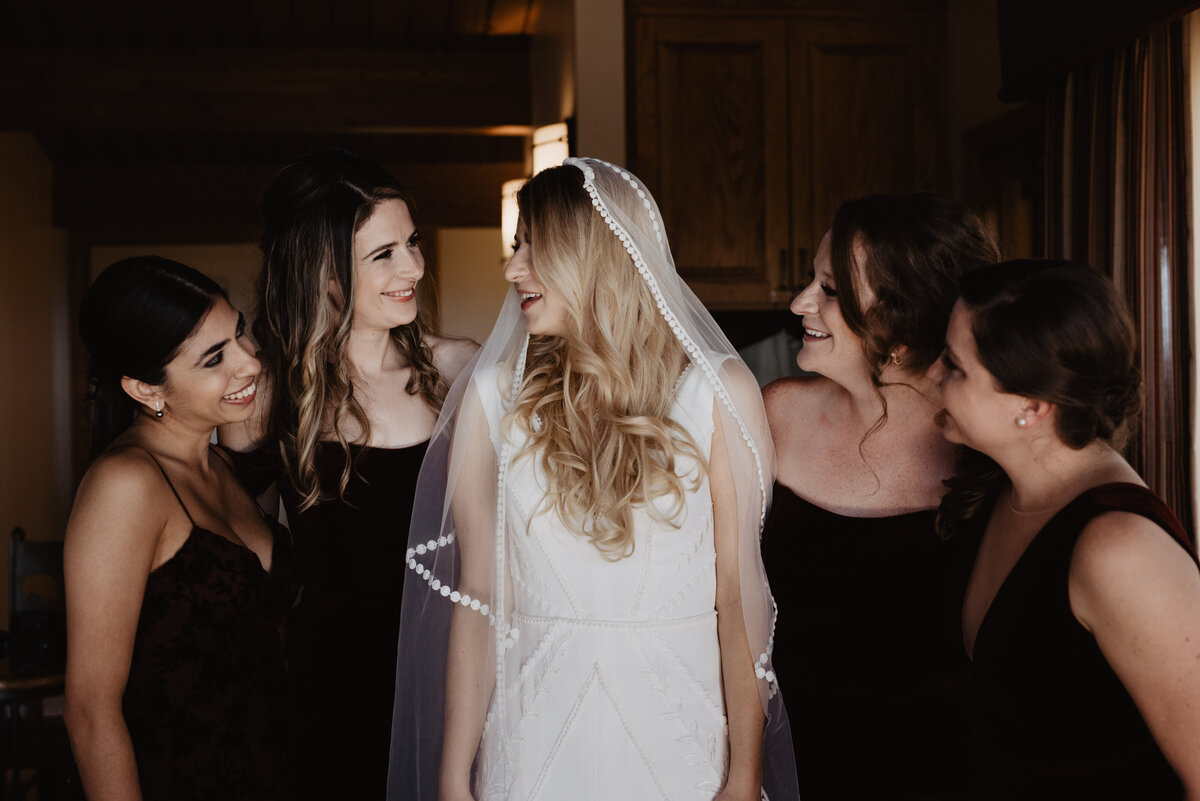 Photographers Jackson Hole capture bride standing with bridesmaids wearing veil