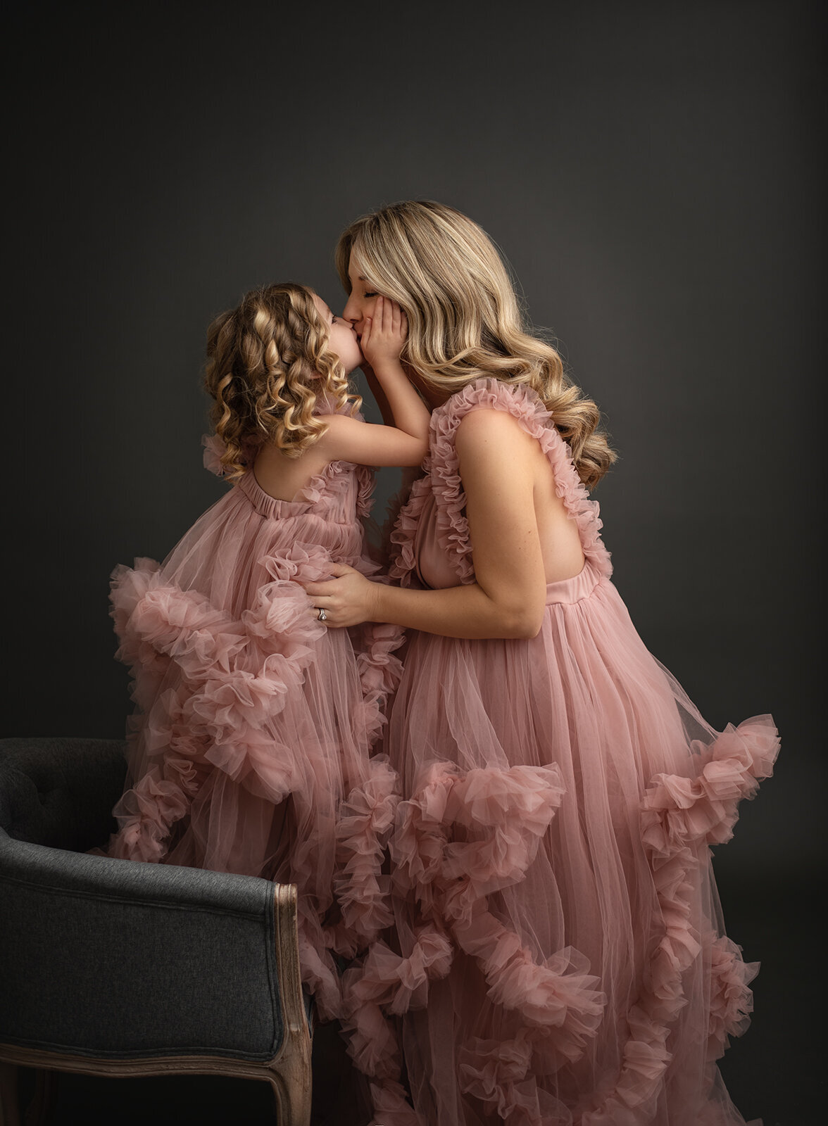 mom and daughter in pink fluffy dresses kissing by st. louis family photographer