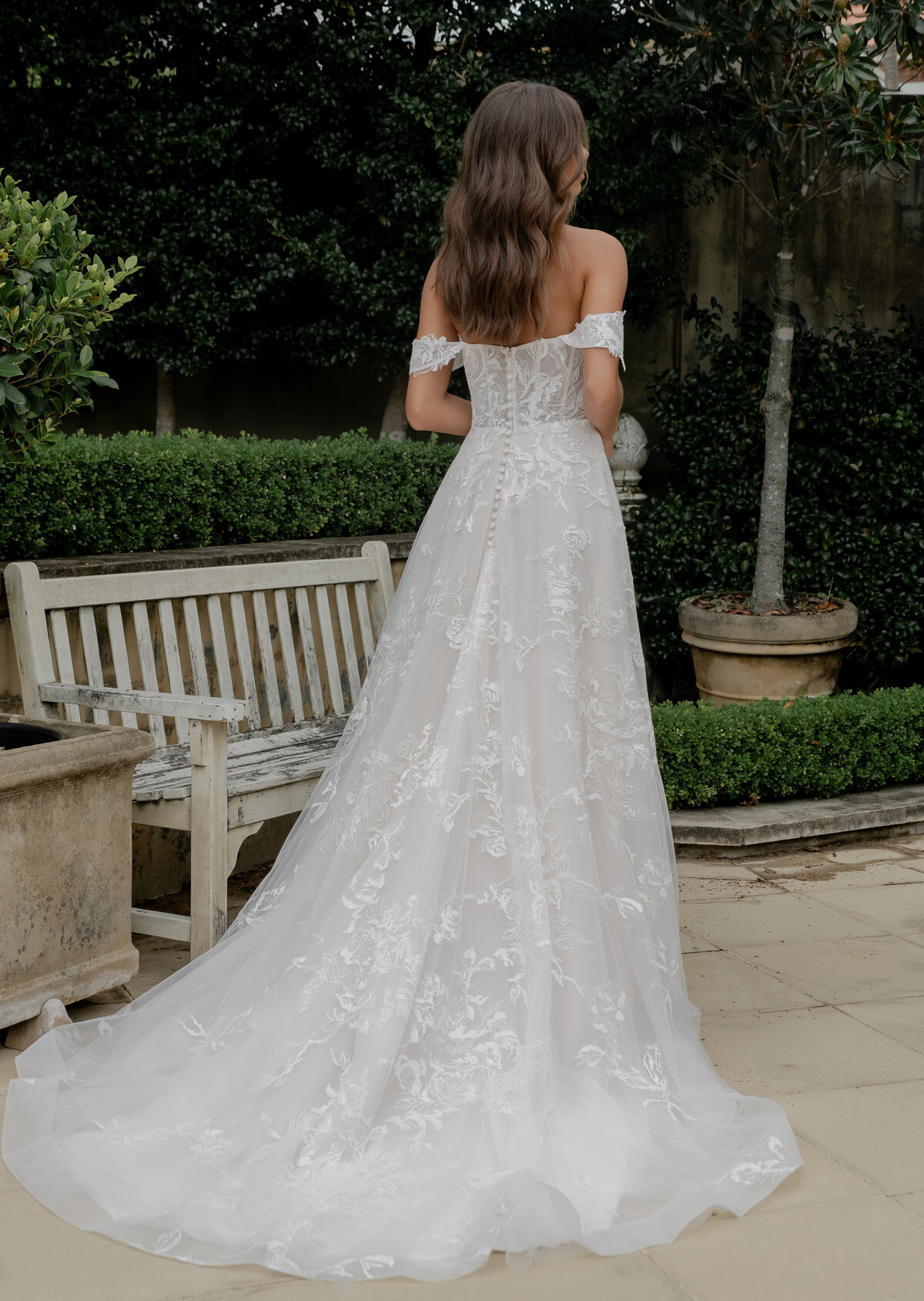 Model in wedding dress standing next to bench