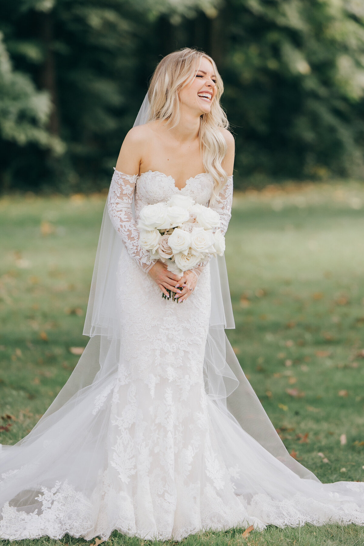 Candid portrait of glamorous bride laughing white holding chic bouquet of roses