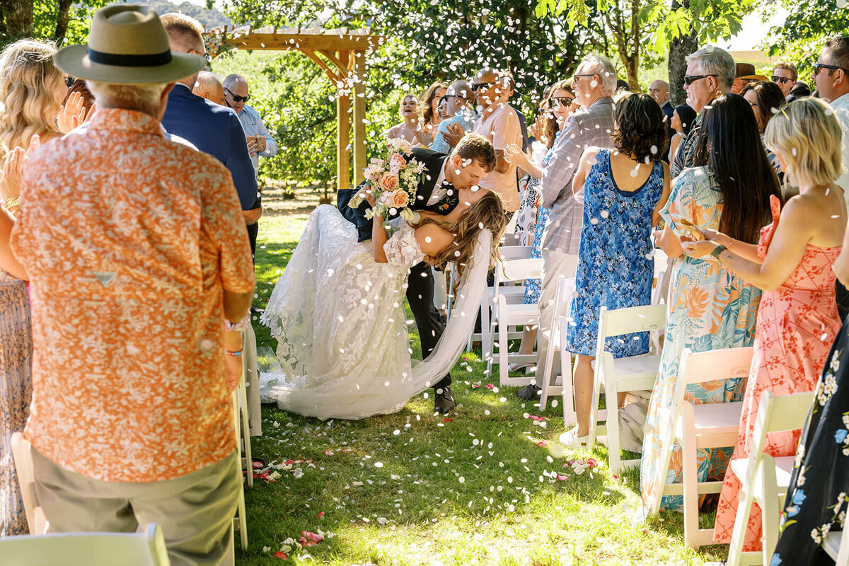 A groom bends his bride and kisses.