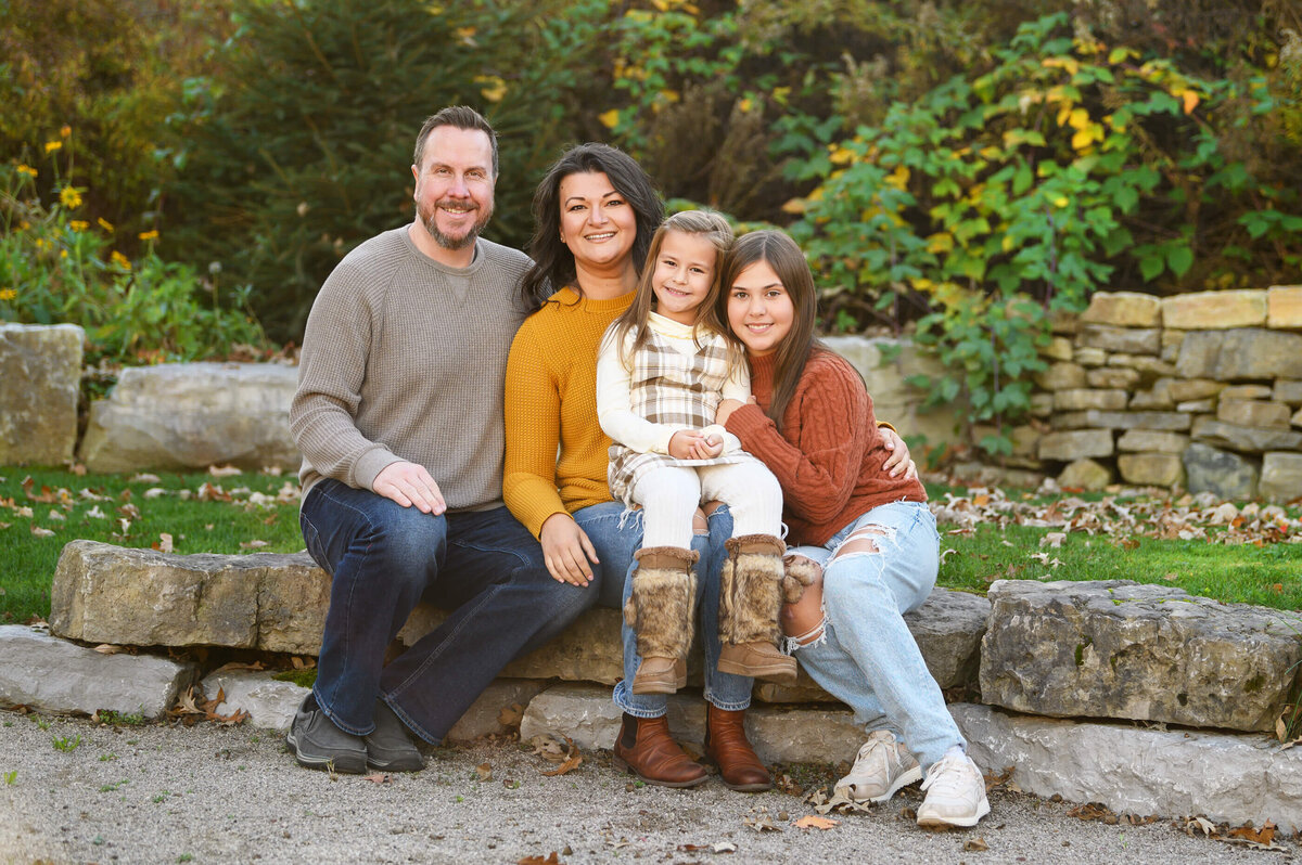 Mom and dad with their two daughters sitting on rocks for their Burlington fall family photos