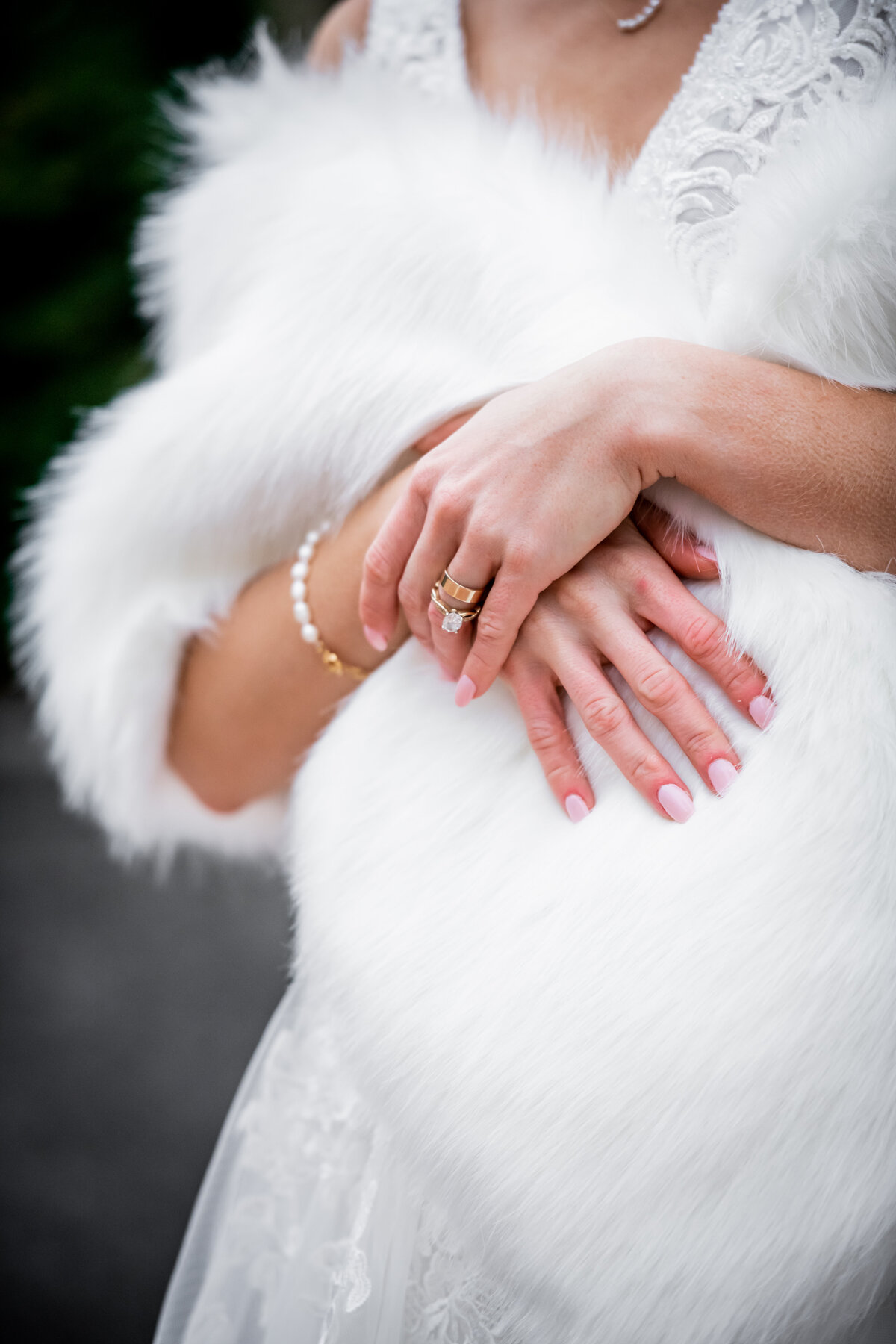 This enchanting bridal portrait captures a serene moment of a bride draped in a luxurious fur wrap, showcasing her sparkling wedding ring. Set against a softly blurred background that accentuates the crisp, wintry atmosphere, the image highlights the intricate details of the ring and the rich texture of the fur, blending classic elegance with a touch of modern sophistication. Ideal for couples seeking inspiration for a winter wedding, this photo beautifully conveys the warmth and romance of a cold-weather celebration.