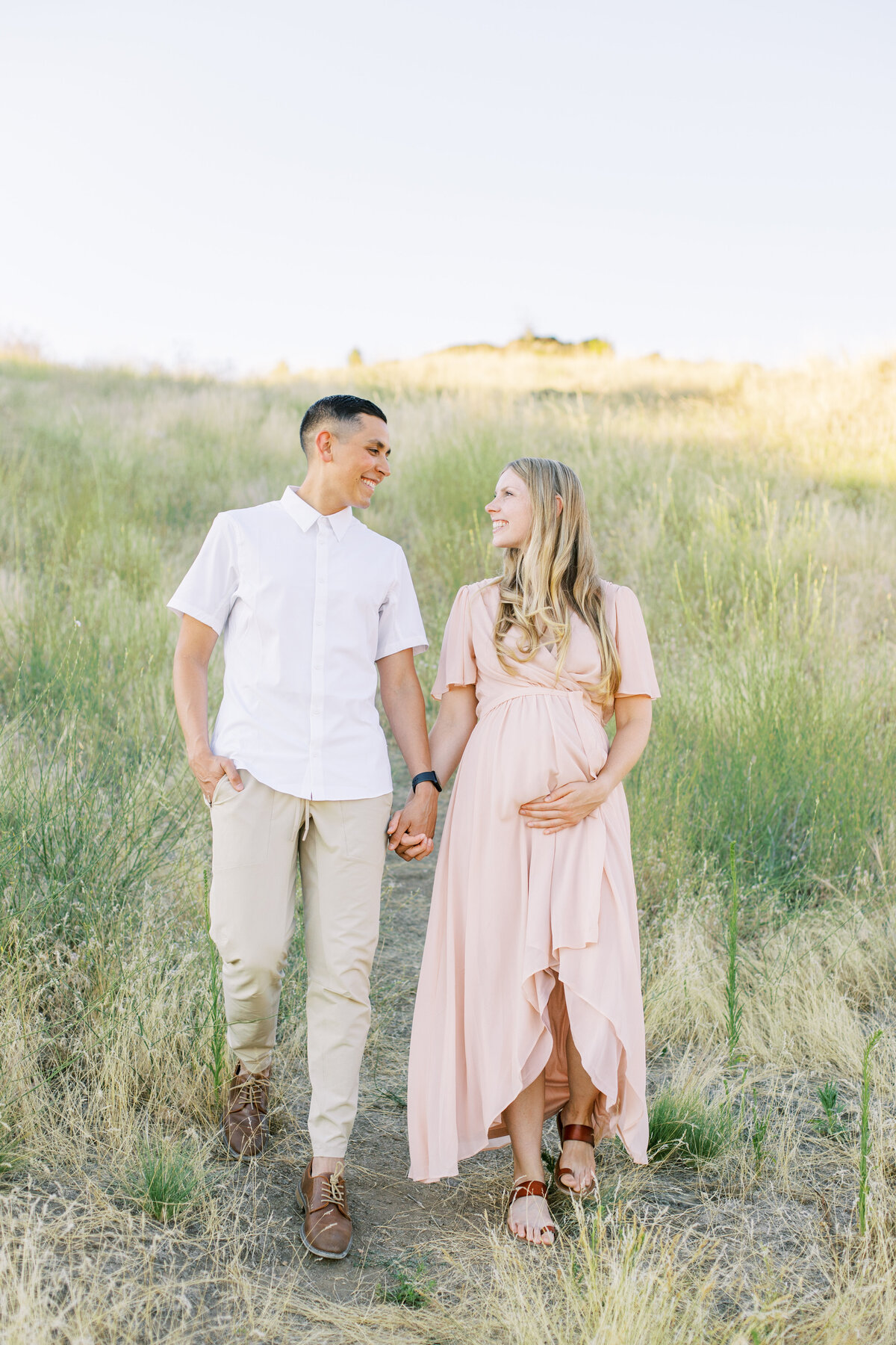 spokane maternity photography with a couple holding hands looking at each other at saltese uplands