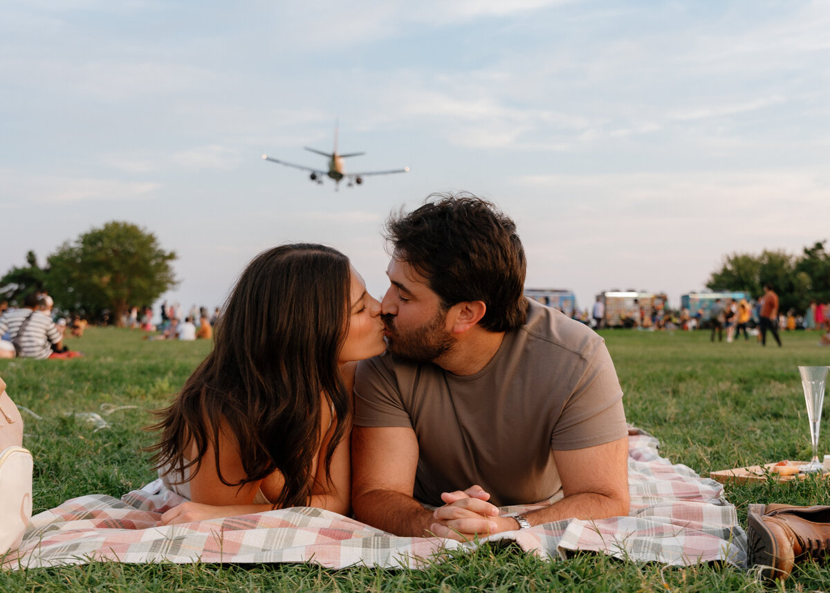 A couple kissing on a picnic blanket