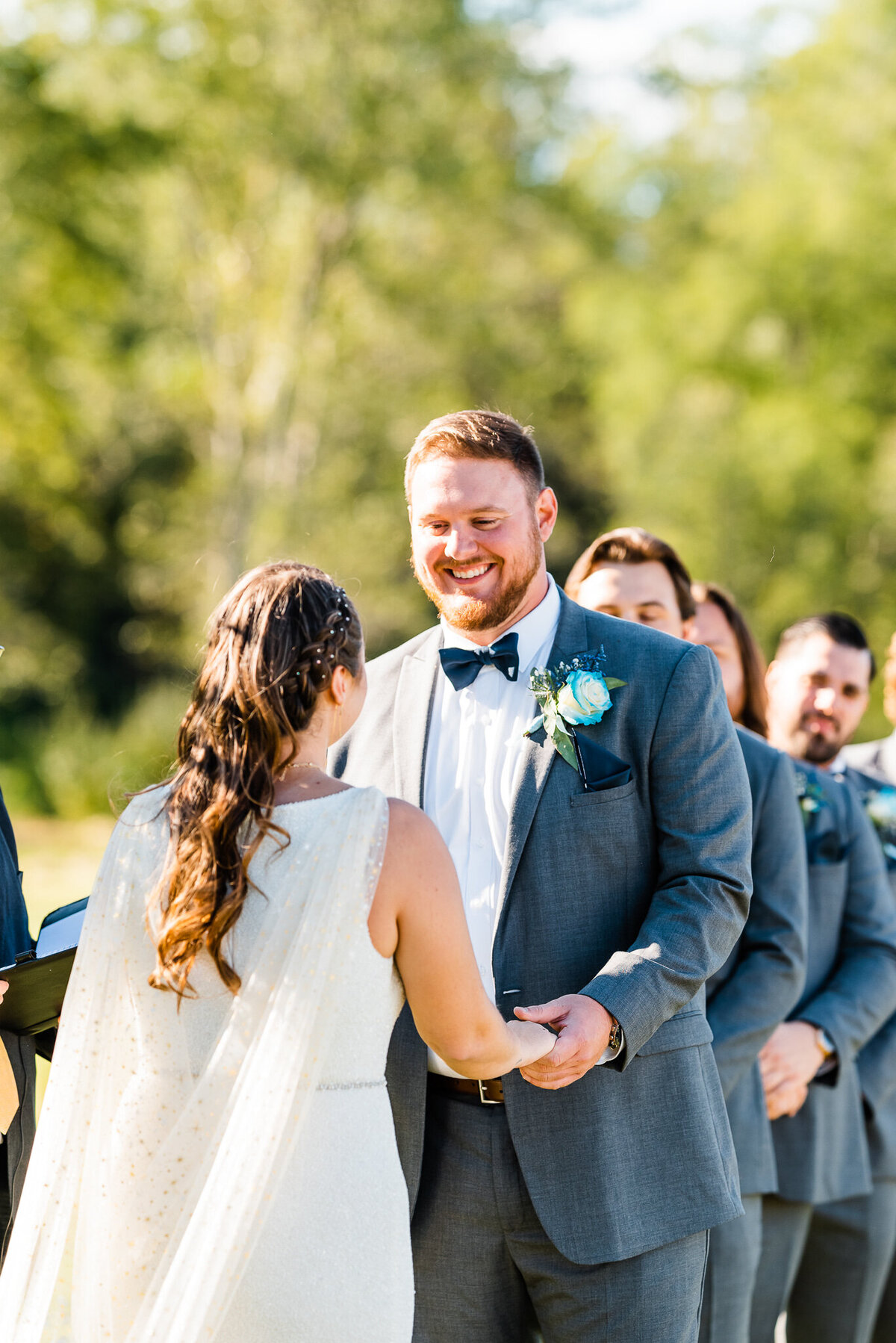 outdoor wedding ceremony in Virginia with groom holding his brides hands and smiling at her while the sun sets over them at Shenandoah wedding venue