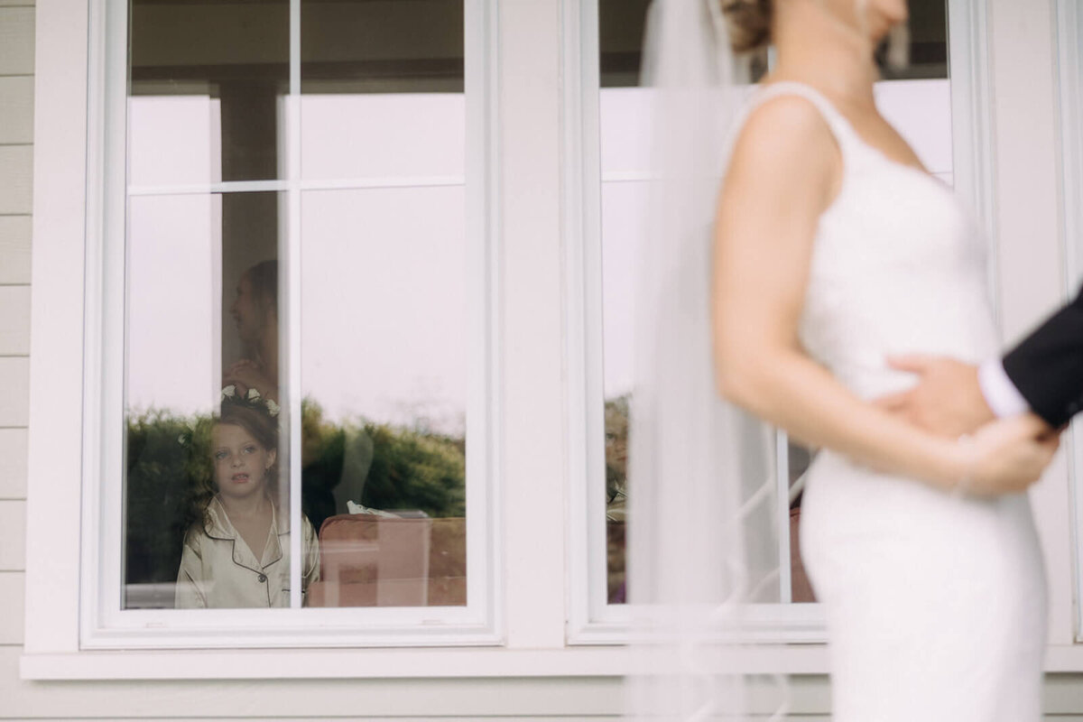 Groom holding bride in front of window