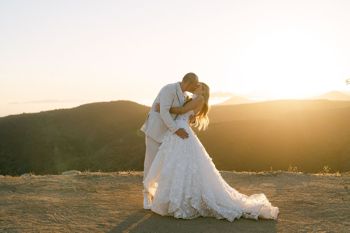 Bride and groom kissing on the cliff at Deer Creek Ridge at their Destination wedding in Malibu