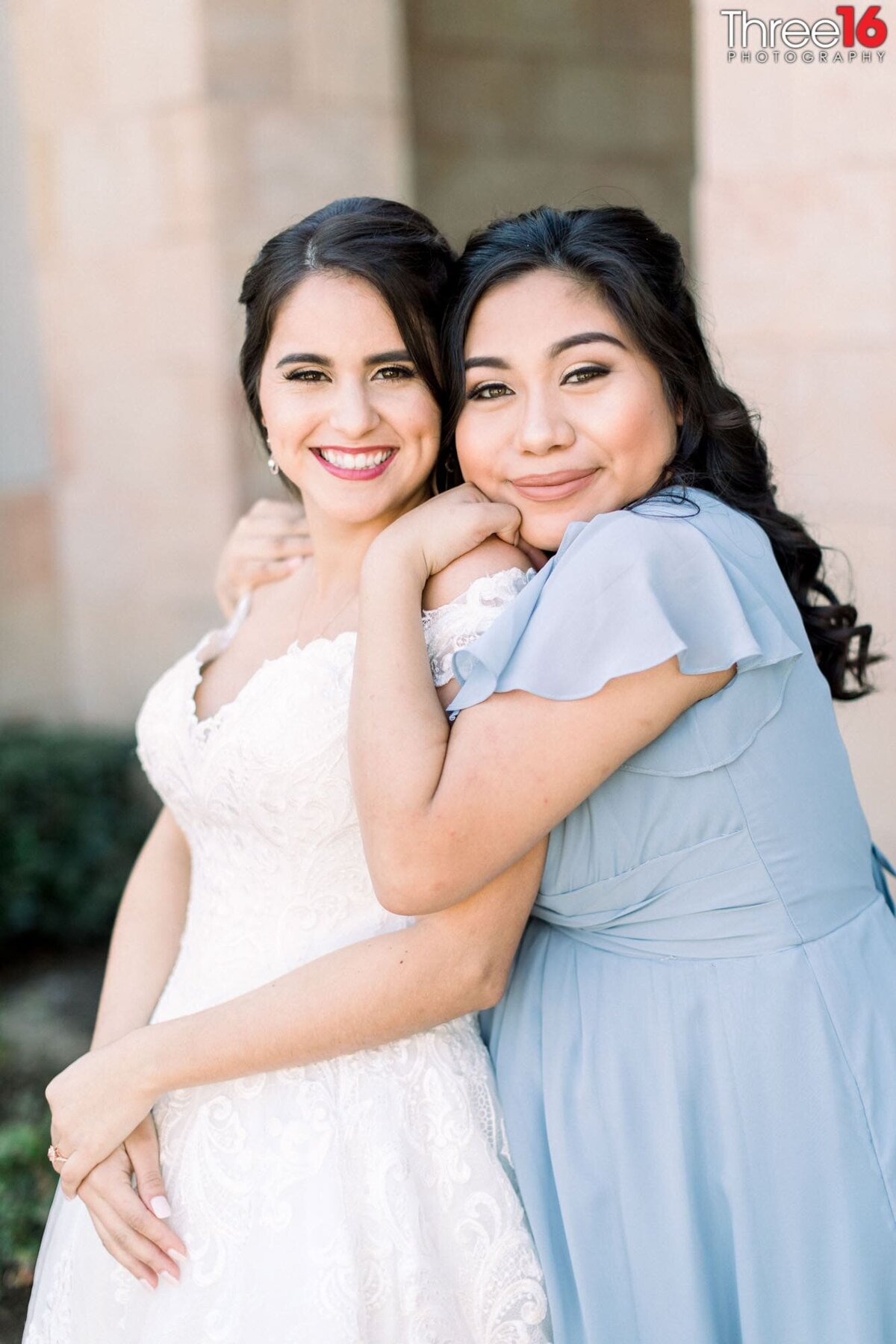Bridesmaid embraces the Bride from behind during photo session