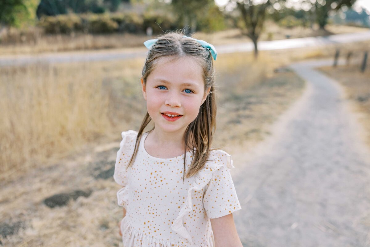 young girl with white dress and bows in her hair at arastradero preserve