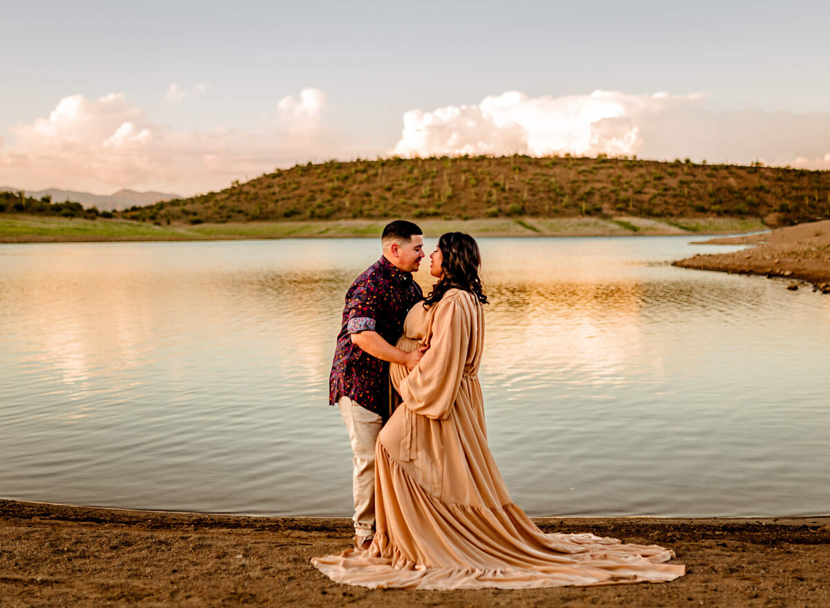 Arizona couple posing in front of Lake Pleasant Arizona for their maternity photographer