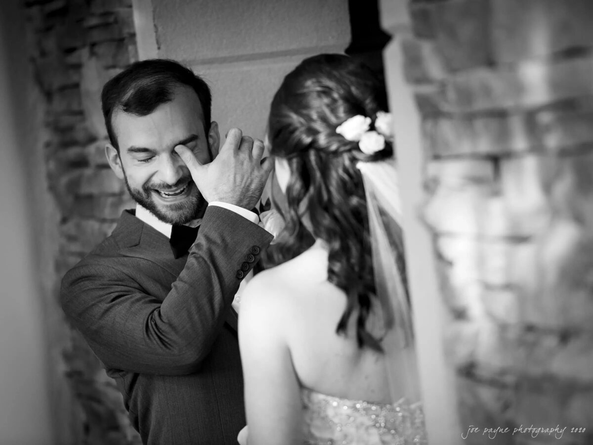 A groom wiping away a tear during the first look with his bride.