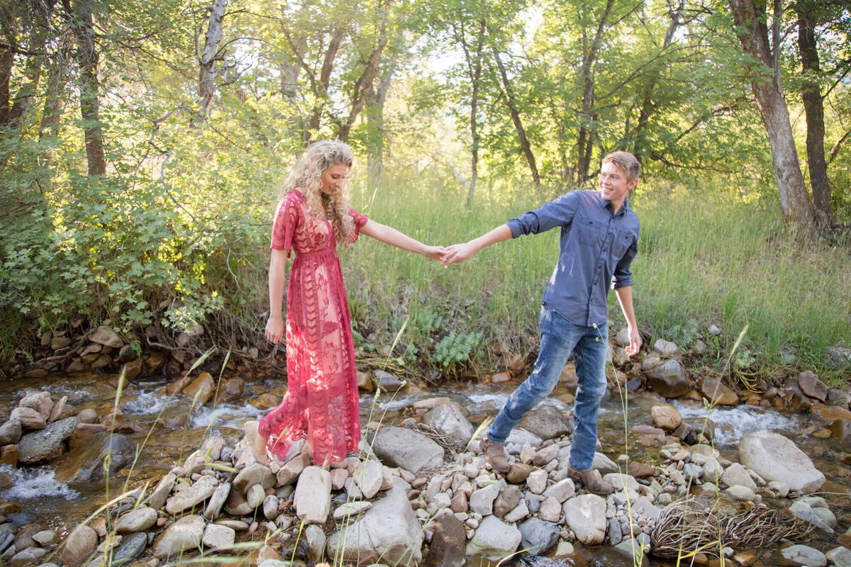 outdoor candid moment of an engaged couple walking along a rocky riverbed