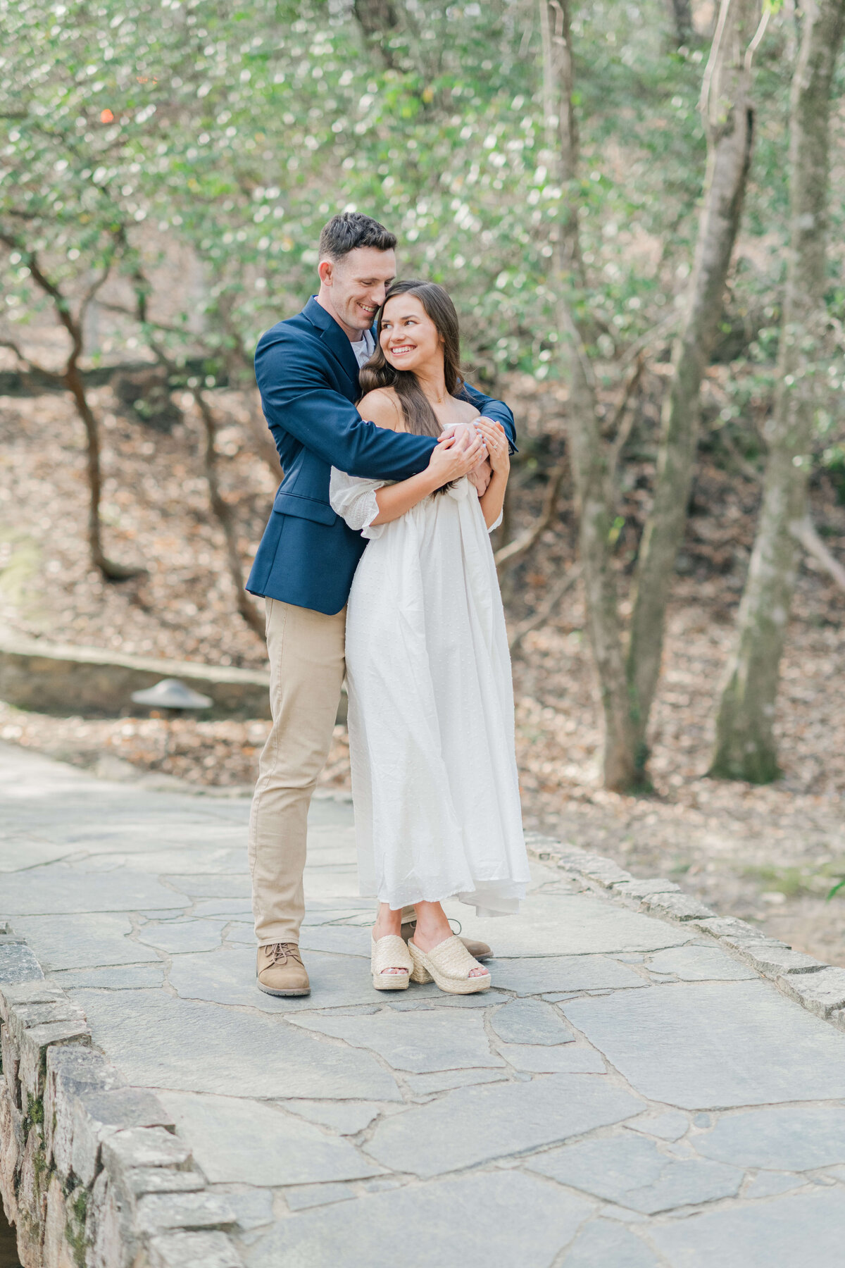 Man holding woman close while they walk on a path in a park