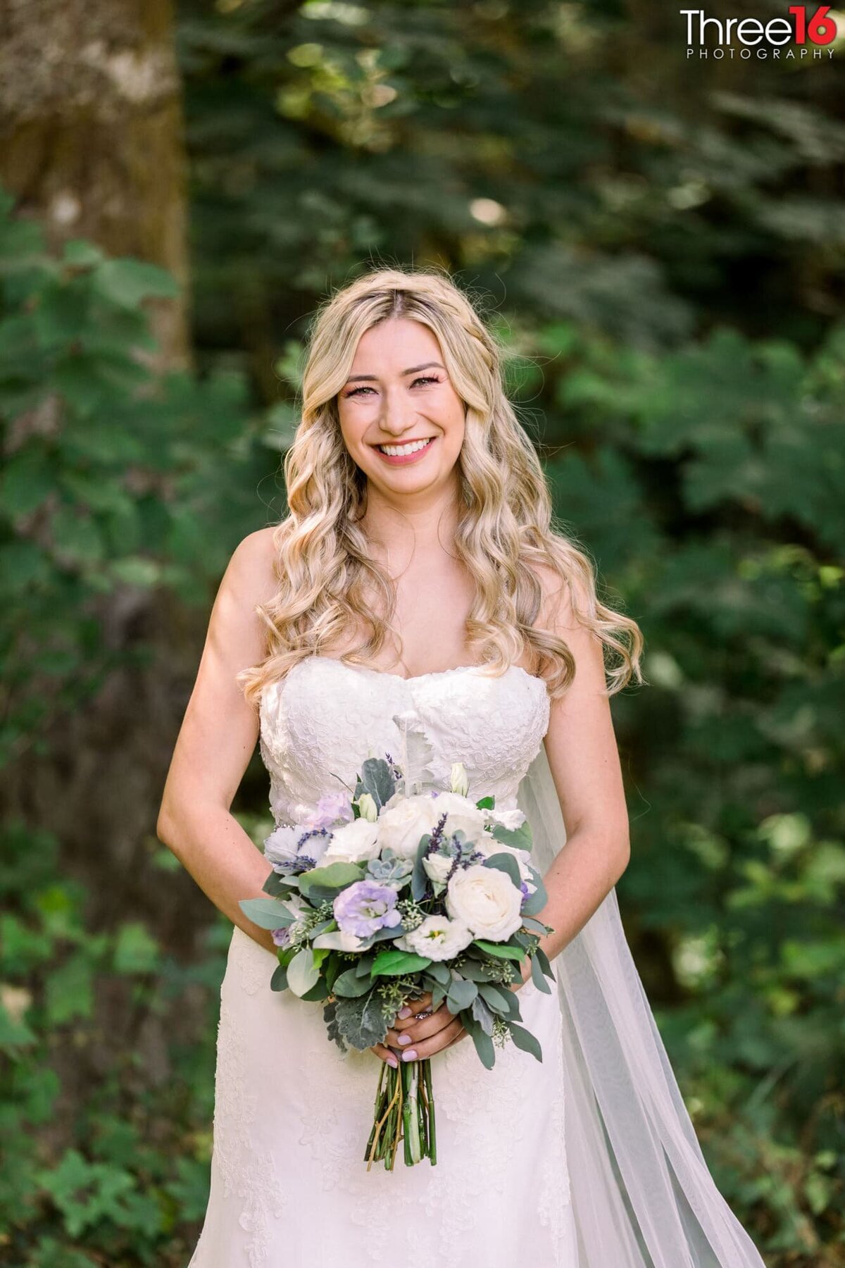 Smiling Bride poses for a photo holding her bouquet