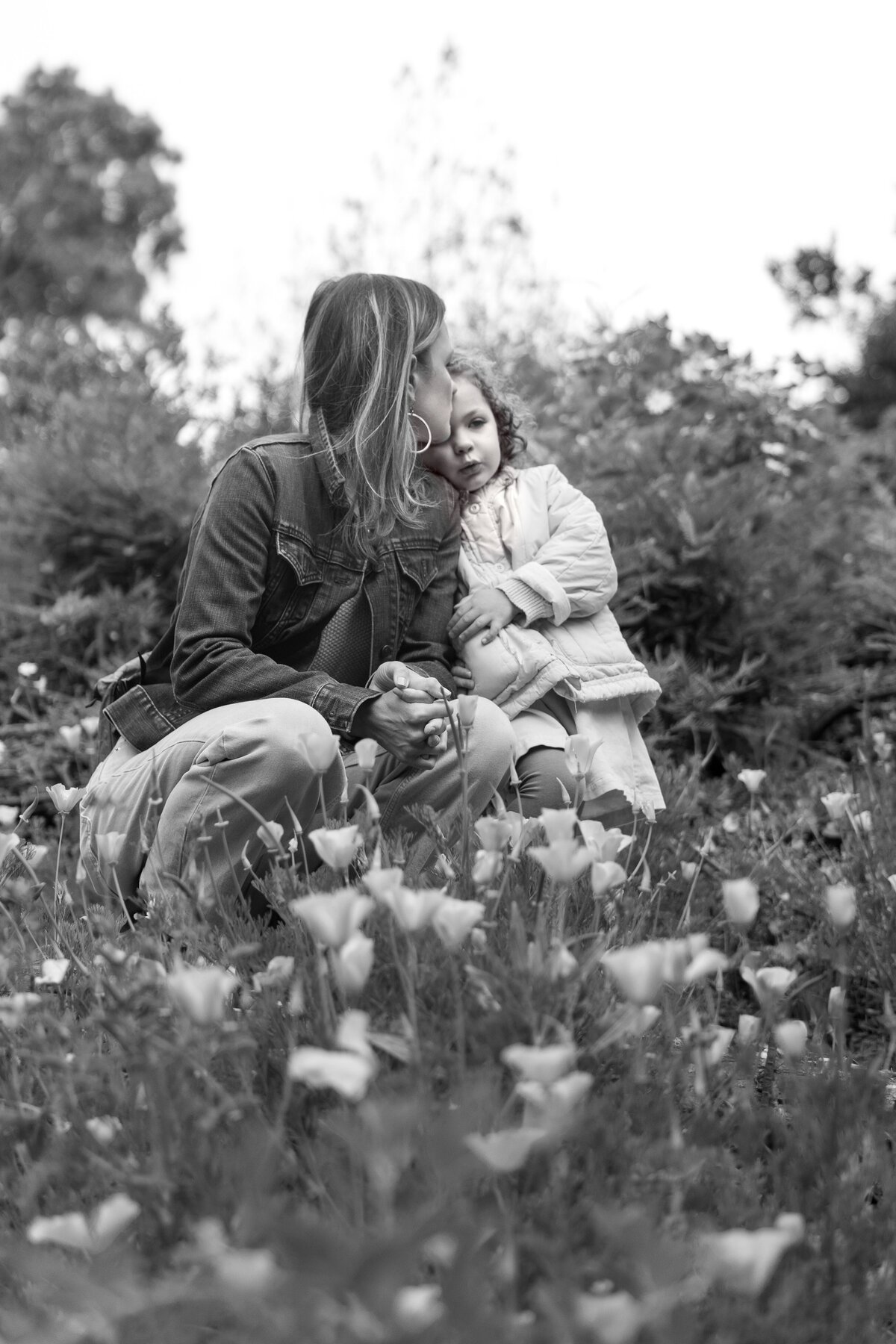 Mother and daughter cuddle in field of poppies