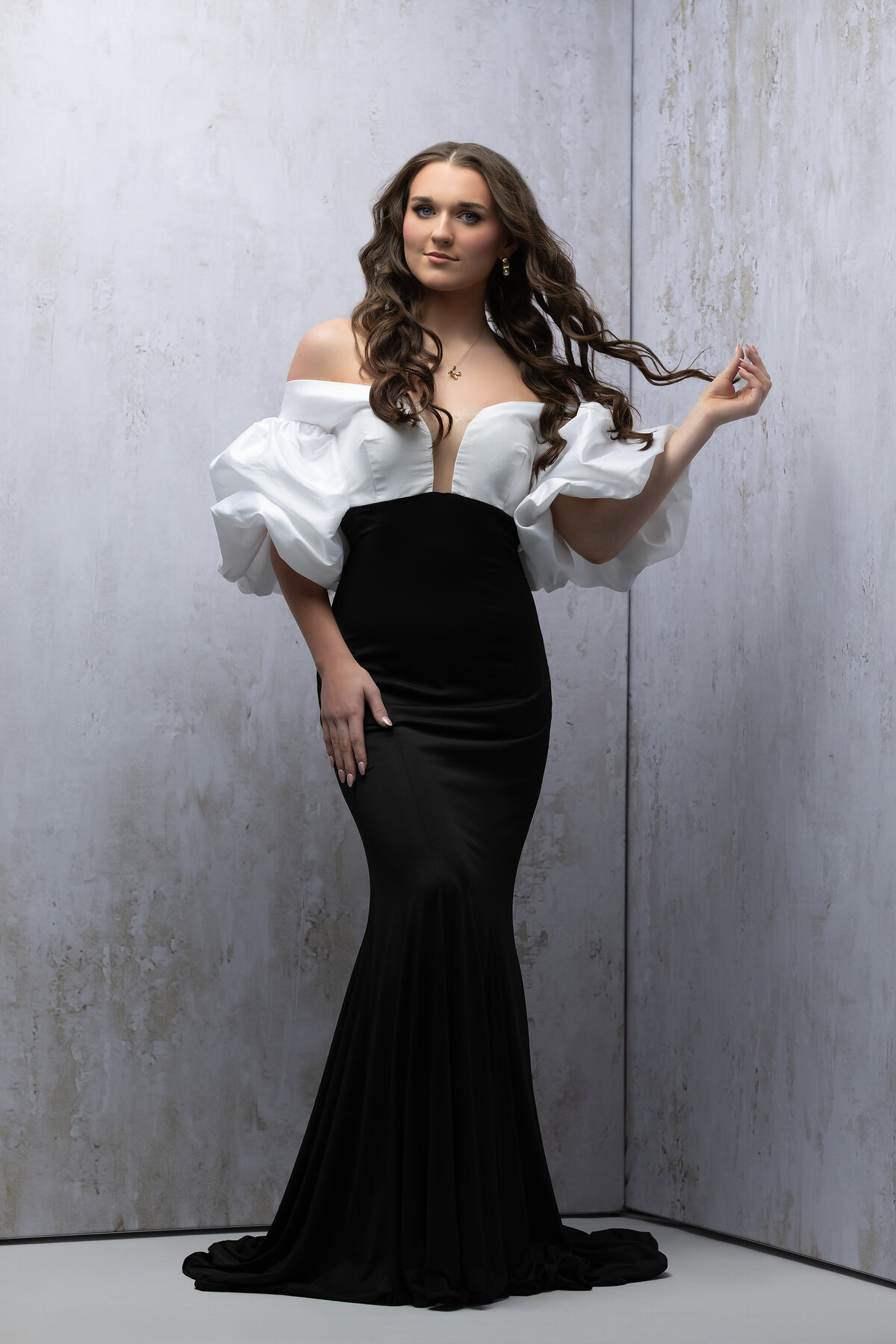 Studio portrait of a high school senior in a black and white gown by a senior photographer Dallas.