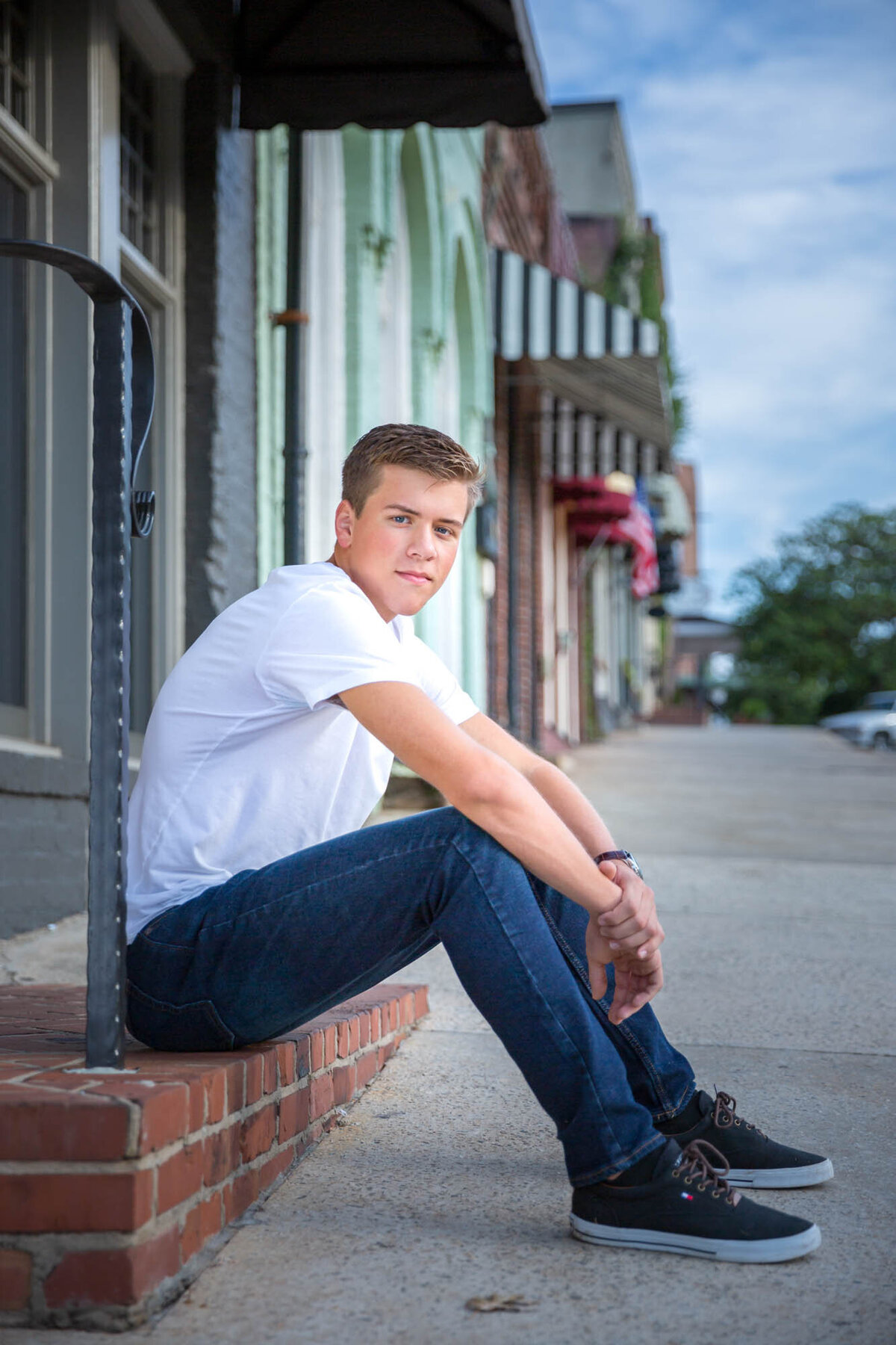 A senior portrait of a guy sitting on the step of a building on Main Street in Senoia, Georgia.