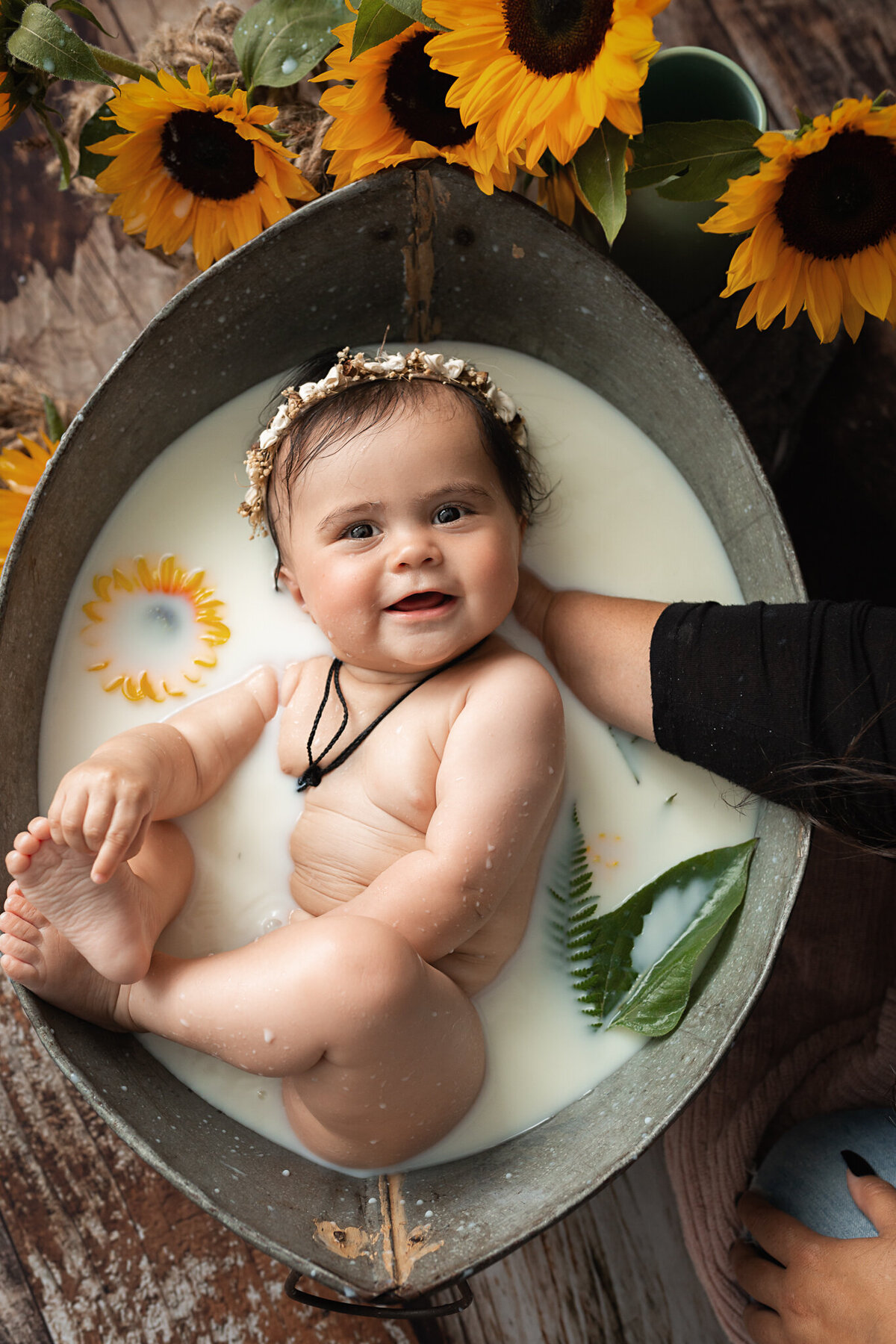happy smiling baby in her milk bath with yellow sunflowers