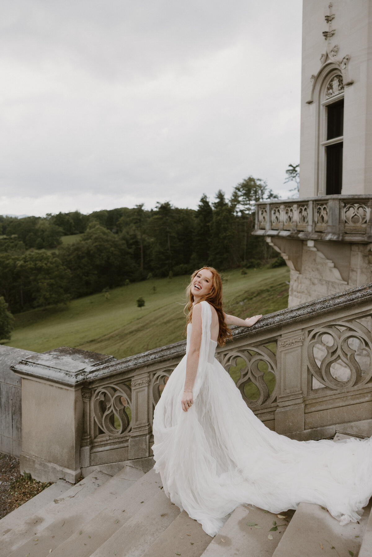 Bride stepping carefully down the Biltmore staircase as her veil and dress catch the soft breeze.