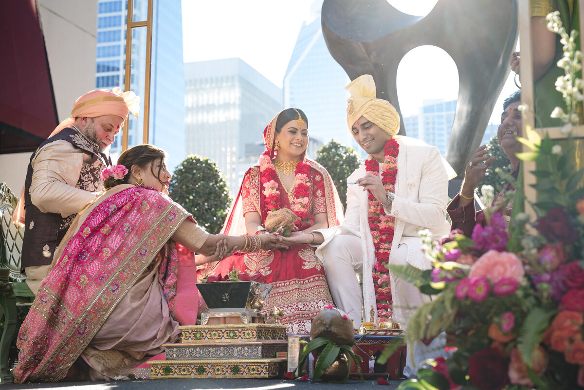 Traditional Indian wedding ceremony at the Grand Bohemian Hotel Charlotte with bride and groom in red lehenga and ivory sherwani during Kanyadaan ritual, captured by DeLong Photography, Charlotte Indian wedding photographers.