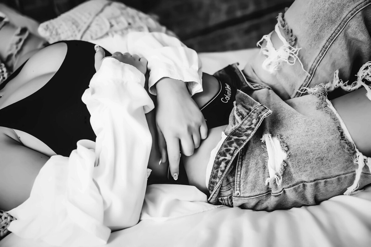 Woman laying on bed in Calvin Klein and jeans for boudoir session with Reva Davis photography