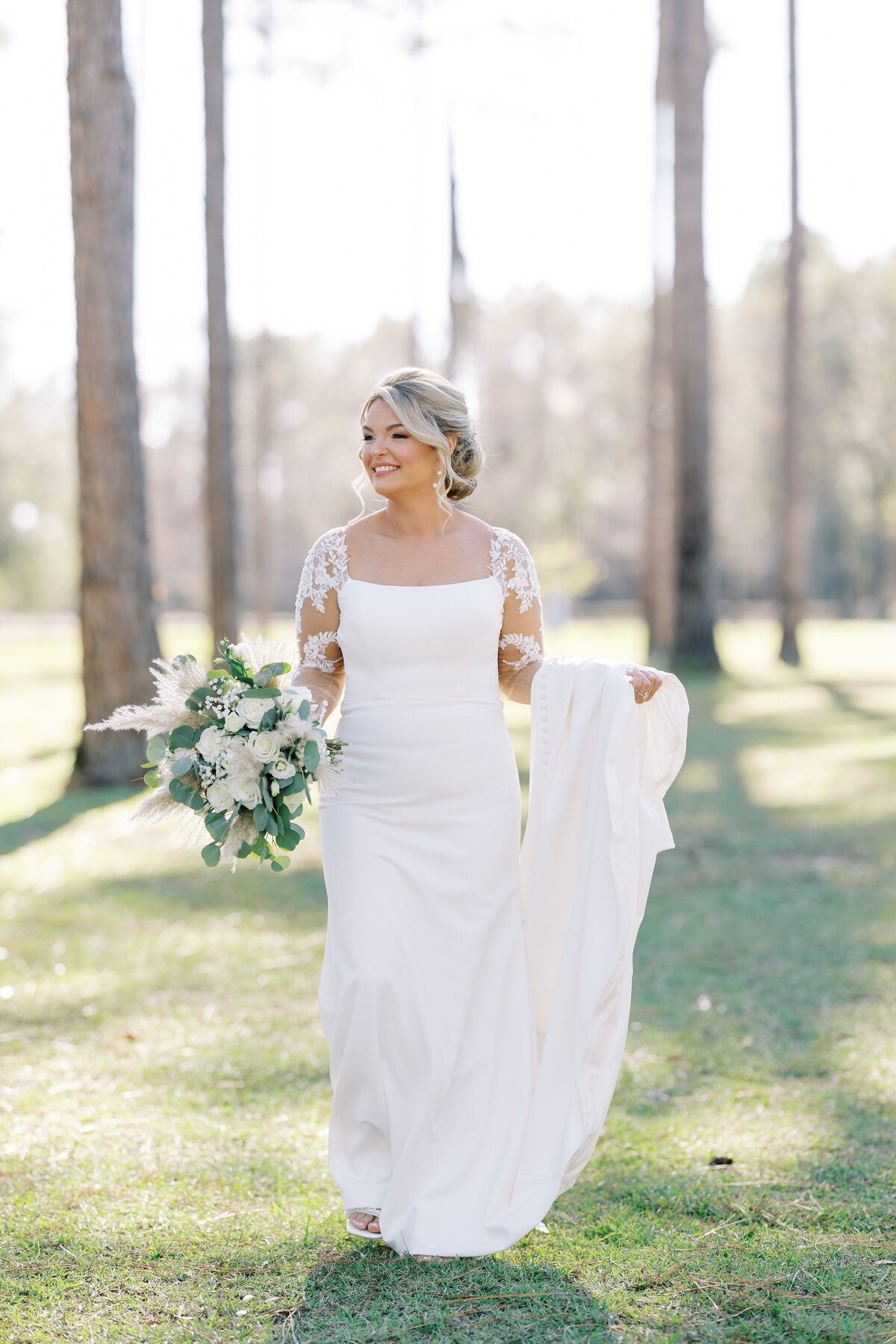 bride smiling in her wedding dress while standing amongst trees