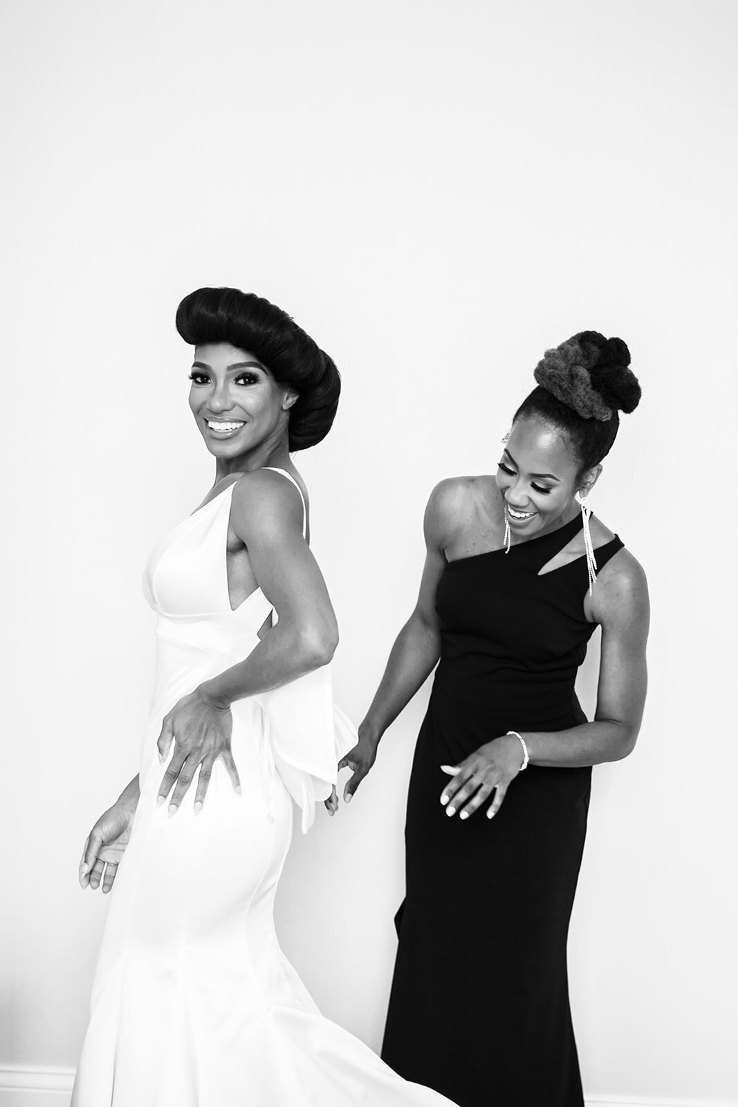 Black and white photo of the bride laughing with a bridesmaid, showcasing joyful wedding moments.