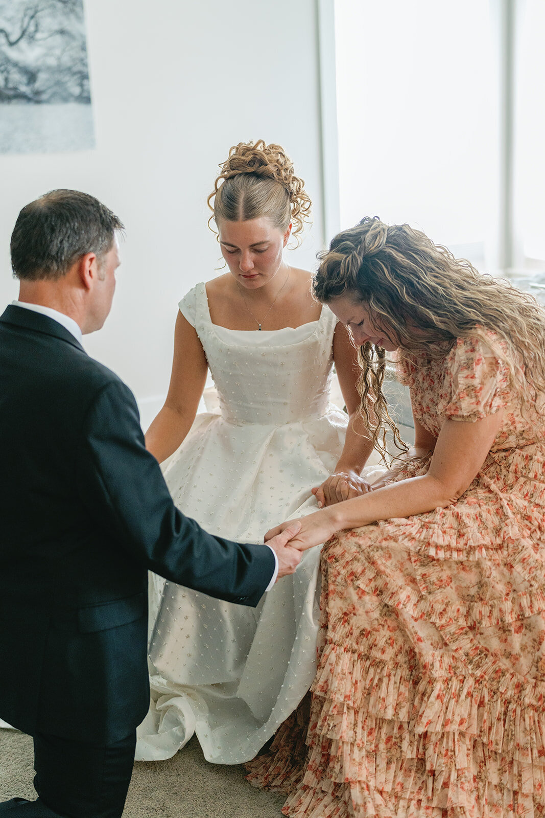 Bride, her mother and father saying a prayer before her wedding