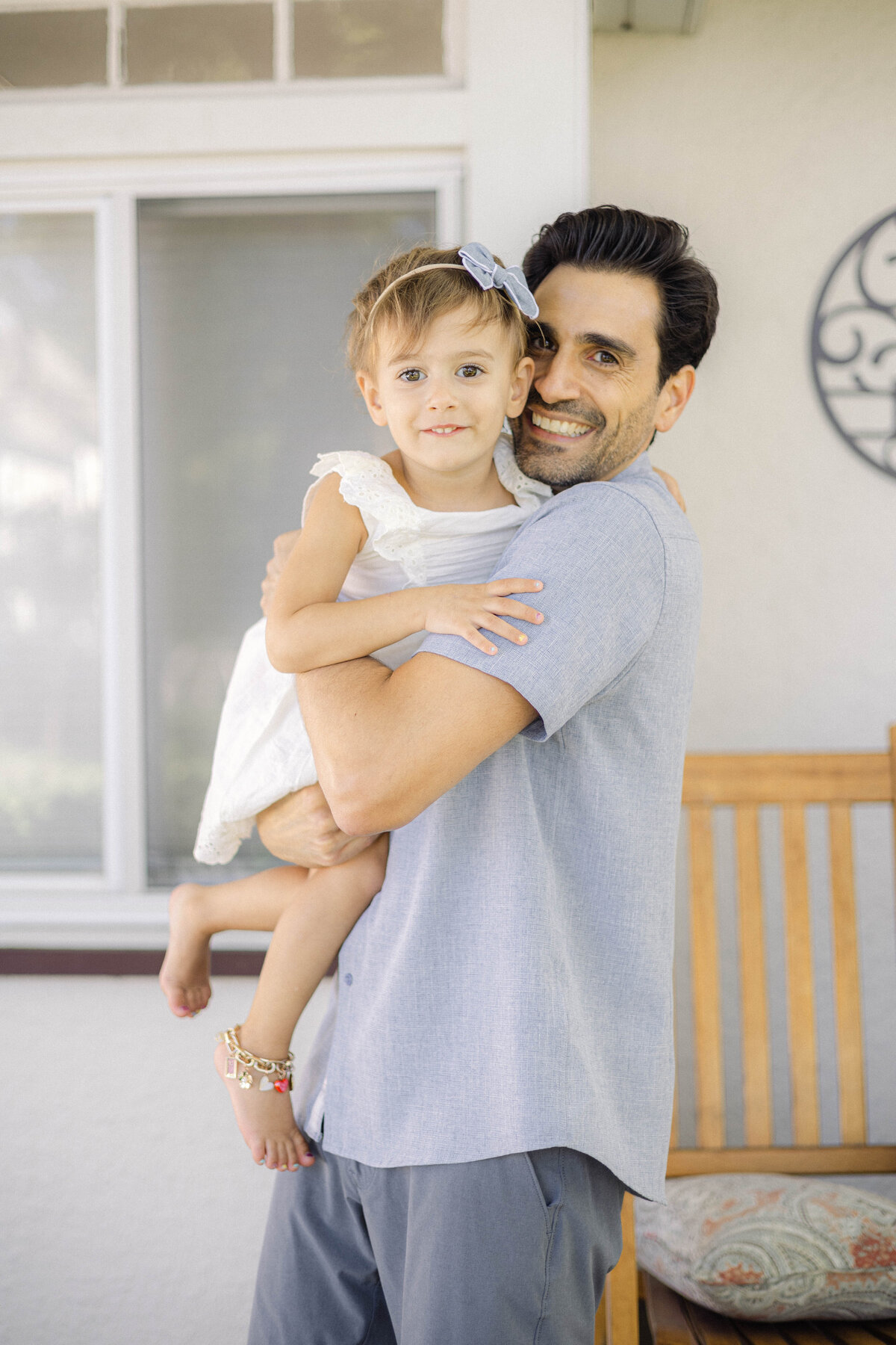 Dad and daughter embracing one another in a big hug outside on the porch.