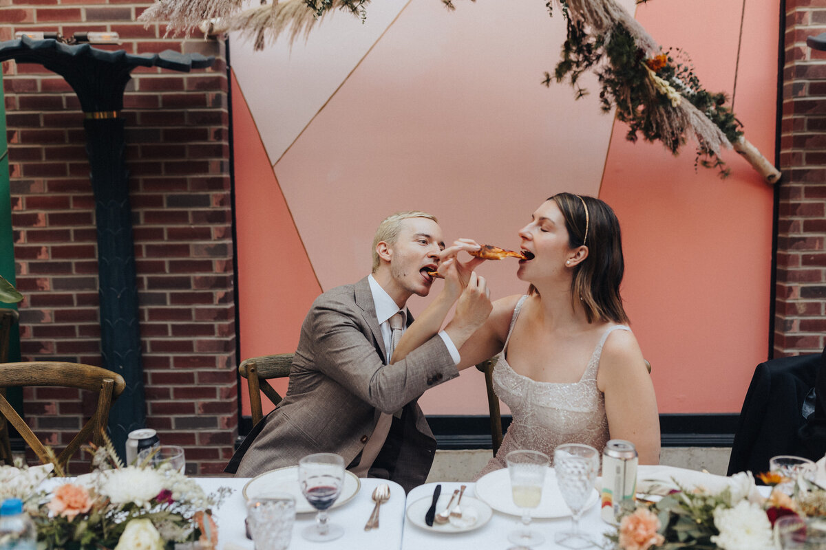 Couple feeding each other pizza at reception